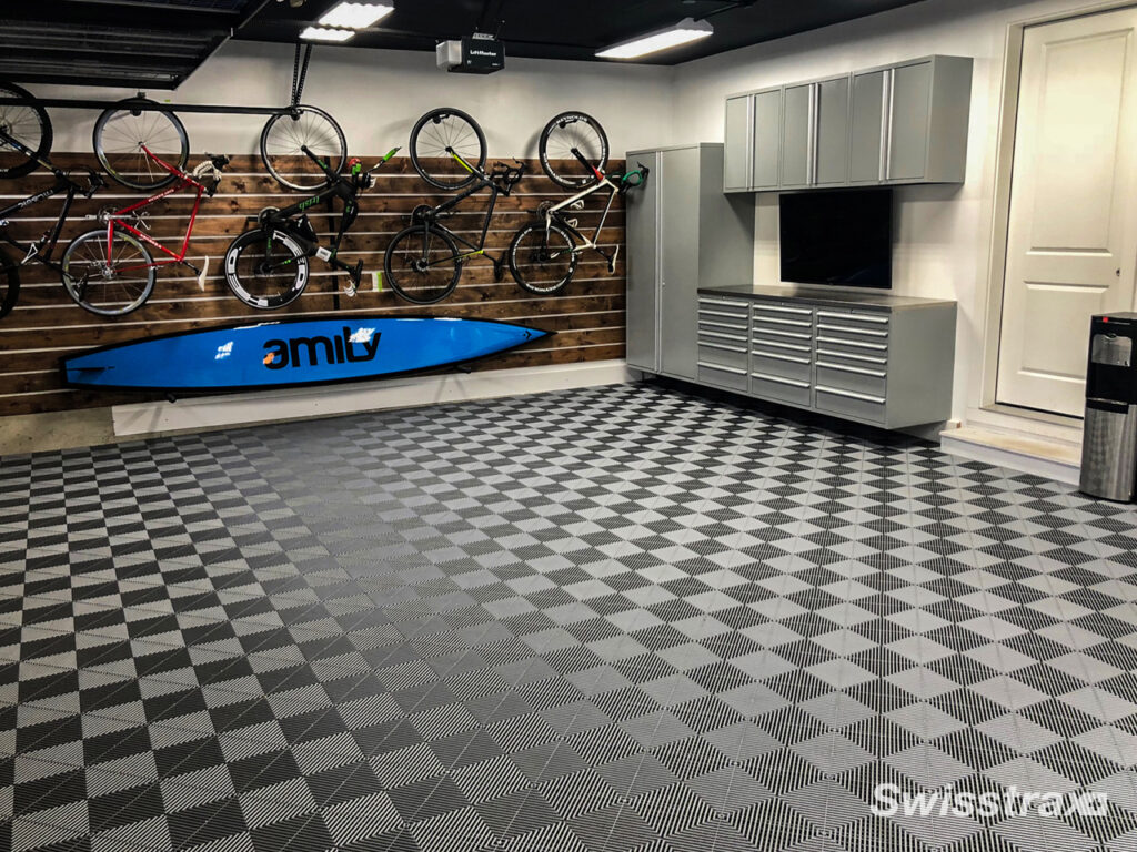 Clean and welcoming garage with cabinets, slatwall, workbench, and SwissTrax flooring