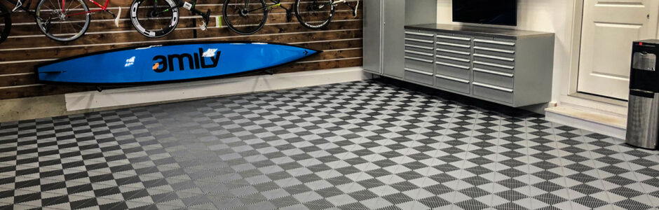 Clean and welcoming garage with cabinets, slatwall, workbench, and SwissTrax flooring