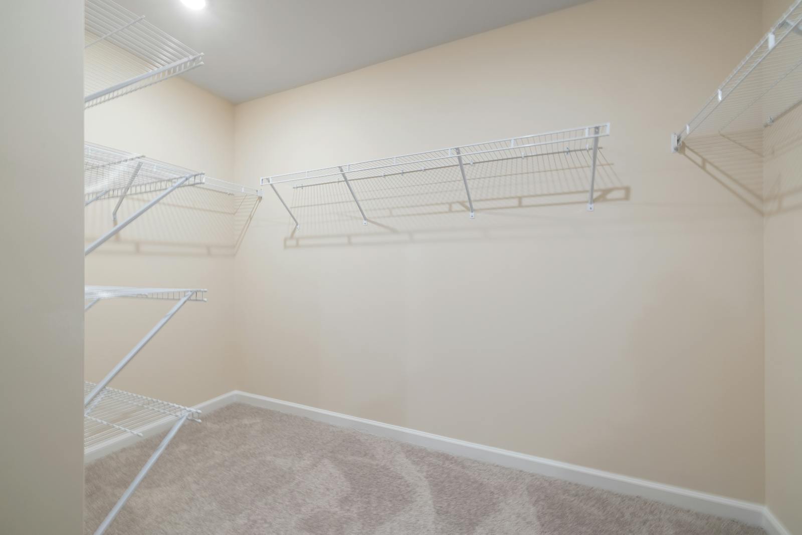 Empty walk-in closet with old ventilated shelving, ready for installation of a beautiful custom system and the homework of reverse decluttering