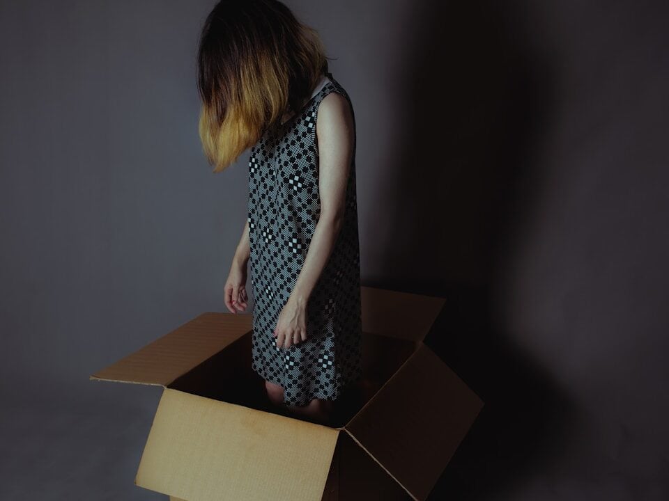 girl in box, tired from decluttering and decision fatigue
